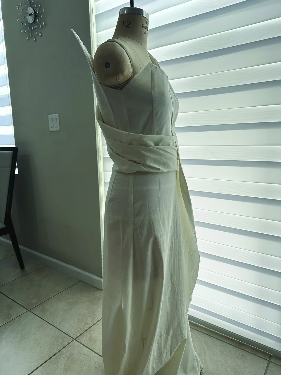 White draped Faith garment in progress on a dress form, front view.